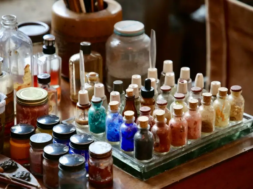 Esta imagen muestra una mesa de un perfumista con muchos potes de colores los cuales usa para crear perfumes para empresas para crear beneficios del marketing olfativo para las empresas que usan estas fragancias.