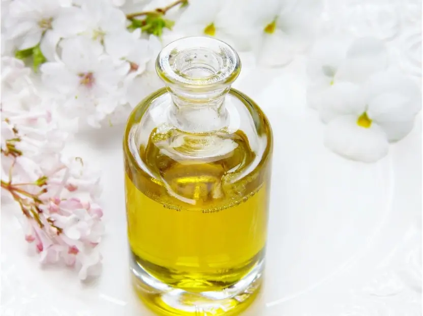Bote transparente con una fragancia de color amarillo a su lado y una flor, hecho para combinar y desarrollar tu marca olfativa.